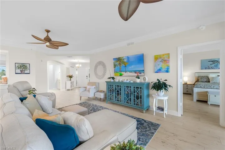 Living room featuring ceiling fan, light wood-type flooring, and crown molding