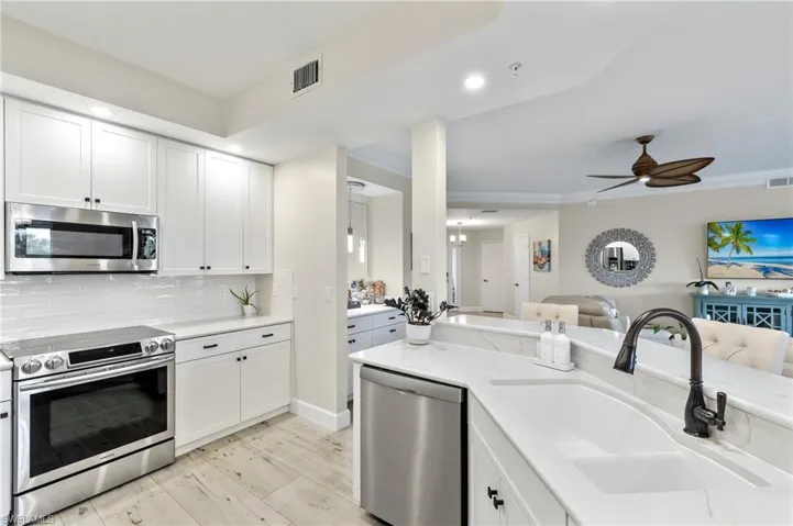 Kitchen with sink, white cabinets, ceiling fan, and stainless steel appliances