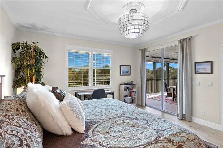 Bedroom featuring a notable chandelier, crown molding, and access to exterior