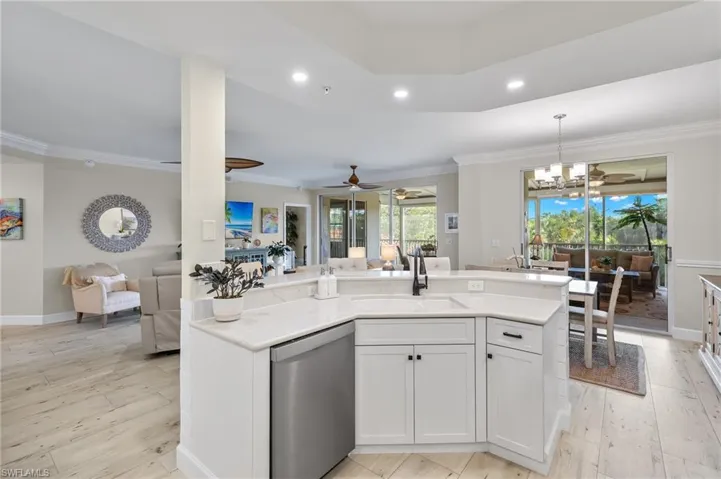 Kitchen with white cabinets, ceiling fan with notable chandelier, dishwasher, hanging light fixtures, and sink