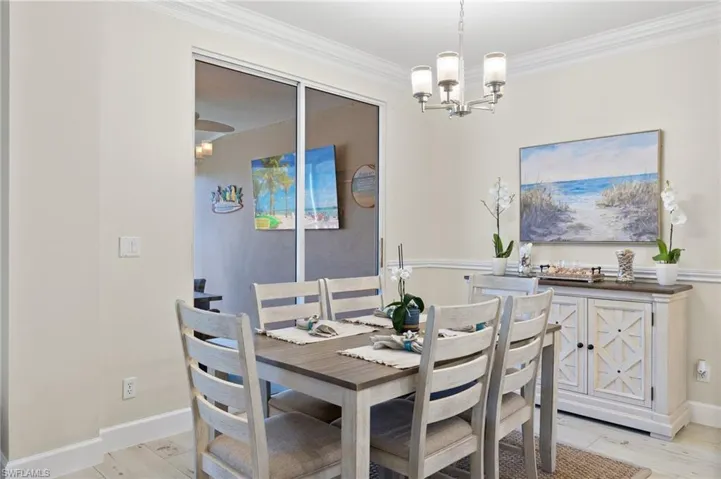 Dining room with a notable chandelier, ornamental molding, and light hardwood / wood-style floors