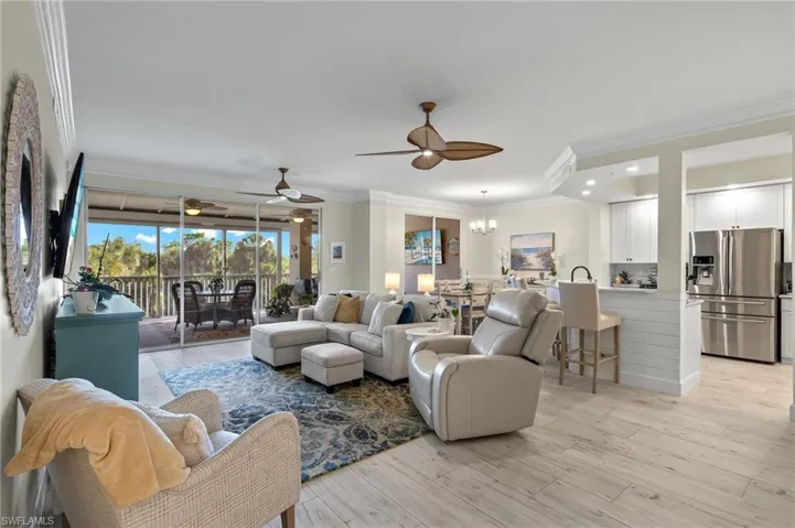 Living room with ornamental molding, light hardwood / wood-style floors, and ceiling fan with notable chandelier