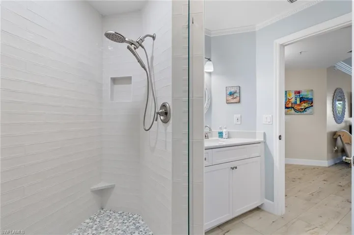 Bathroom with tiled shower, crown molding, tile flooring, and vanity