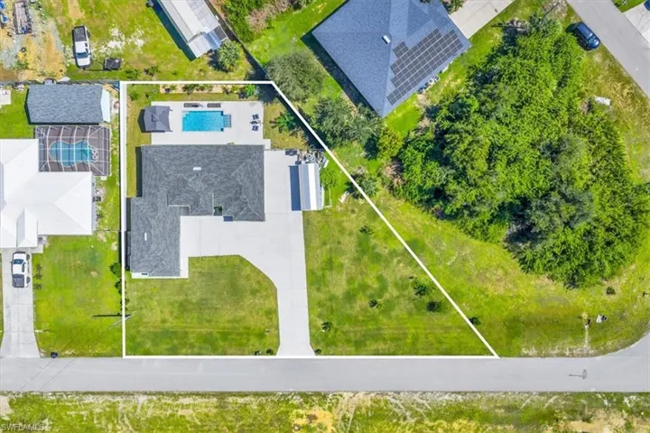 Aerial view of property and surrounding area featuring a pool area and property parcel outlined