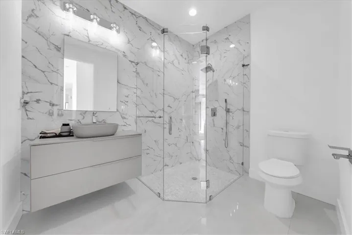 Full bathroom featuring vanity, a marble finish shower, recessed lighting, and tile patterned flooring