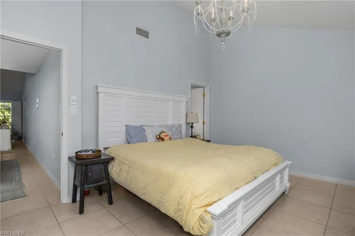 Bedroom featuring light tile patterned flooring, a high ceiling, and a chandelier