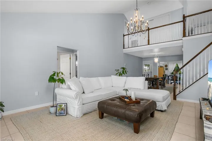Living area featuring light tile patterned flooring, stairs, a high ceiling, and a chandelier