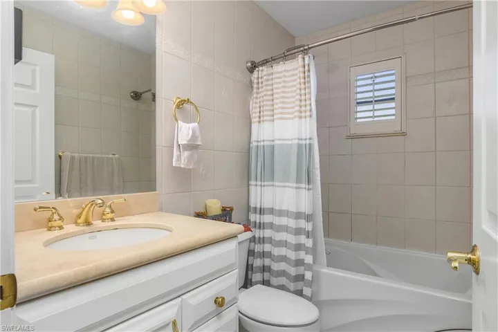 Full bath with shower / tub combo, vanity, and tile walls