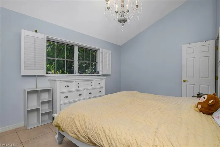 Bedroom with vaulted ceiling, light tile patterned floors, and a chandelier