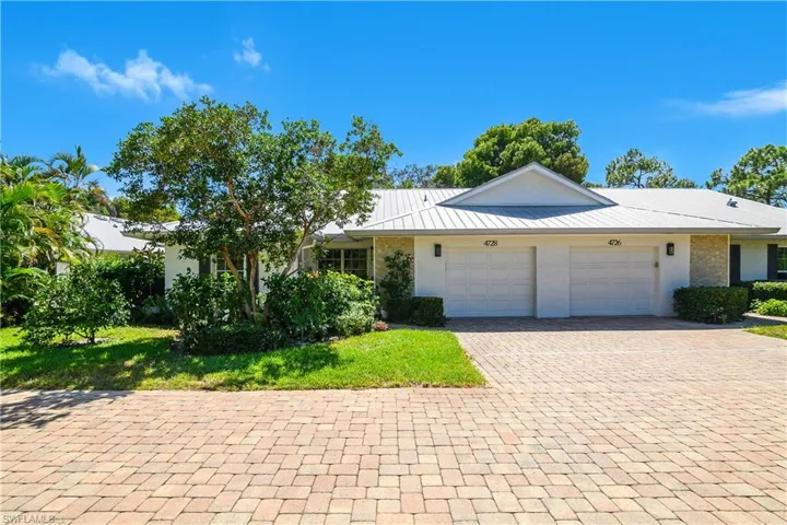 Single story home featuring decorative driveway, a garage, a metal roof, and a front lawn
