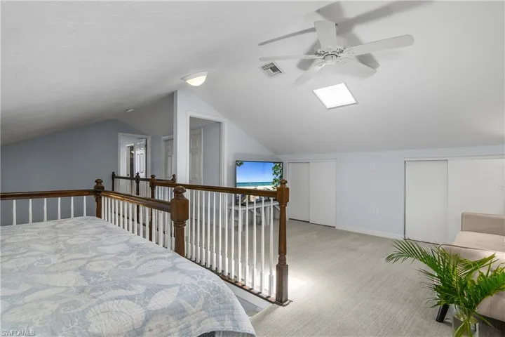 Carpeted bedroom featuring multiple closets, lofted ceiling, ceiling fan, and a textured ceiling