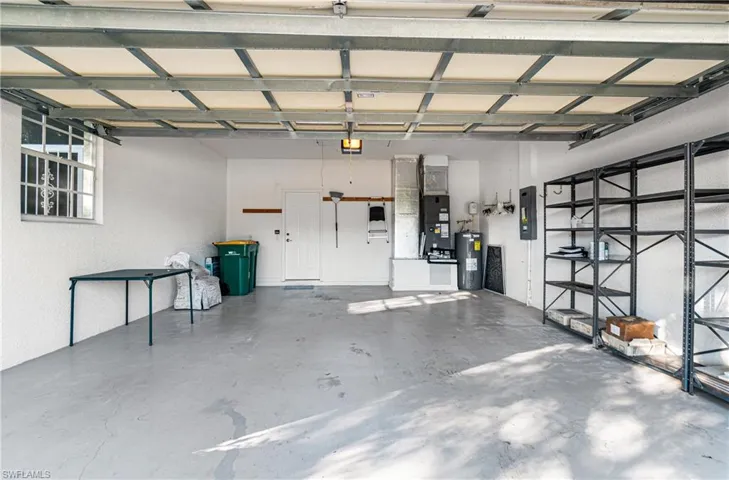 Garage featuring water heater, a textured wall, and electric panel