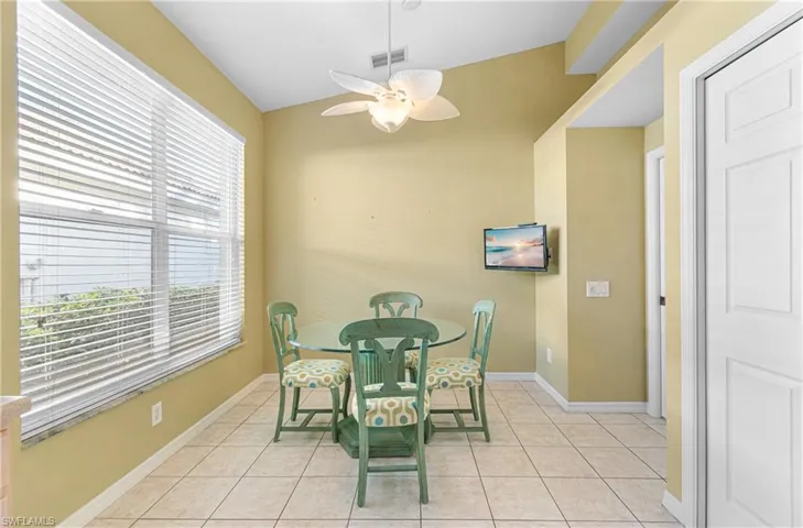 Dining area featuring light tile patterned floors, vaulted ceiling, and a ceiling fan