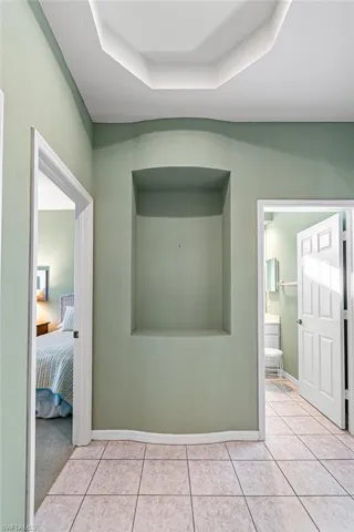 Hallway with a raised ceiling and light tile patterned flooring