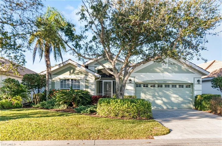 Exterior of house with a front lawn, concrete driveway, an attached garage,with mature, lush landscaping