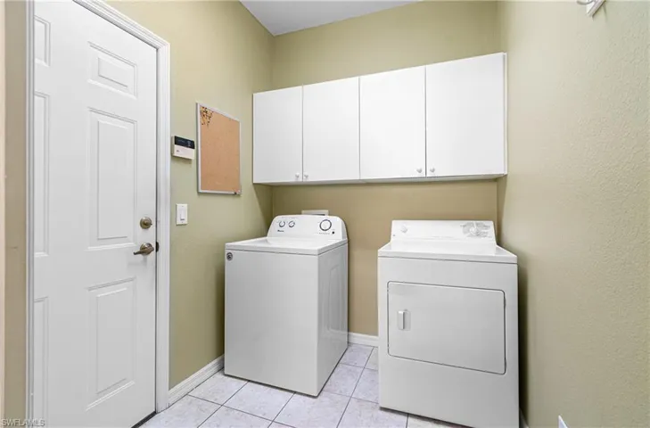 Laundry room with cabinet space, washer and dryer, and light tile floors