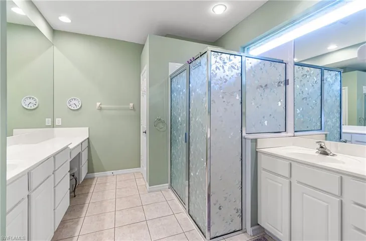 Bathroom with two vanities, a stall shower, light tile patterned floors, and recessed lighting