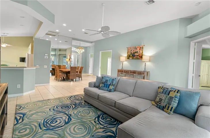 Living room with a ceiling fan, light tile patterned floors, and a chandelier