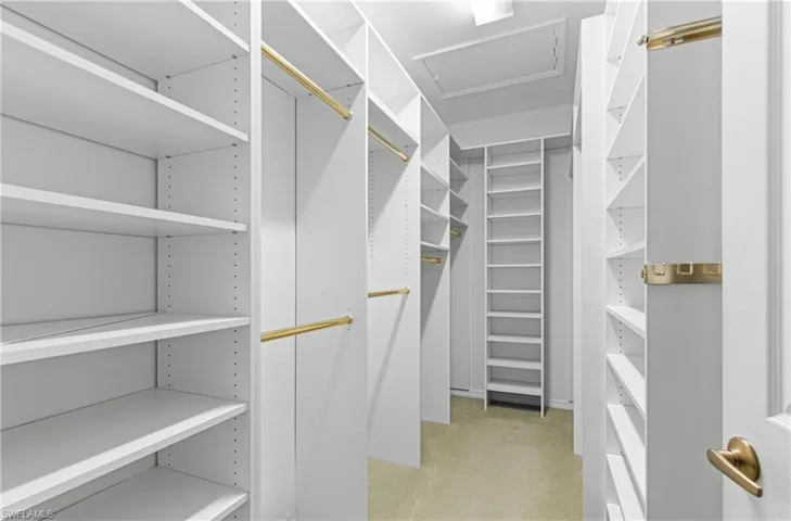 Walk in closet featuring custom built in shelving.