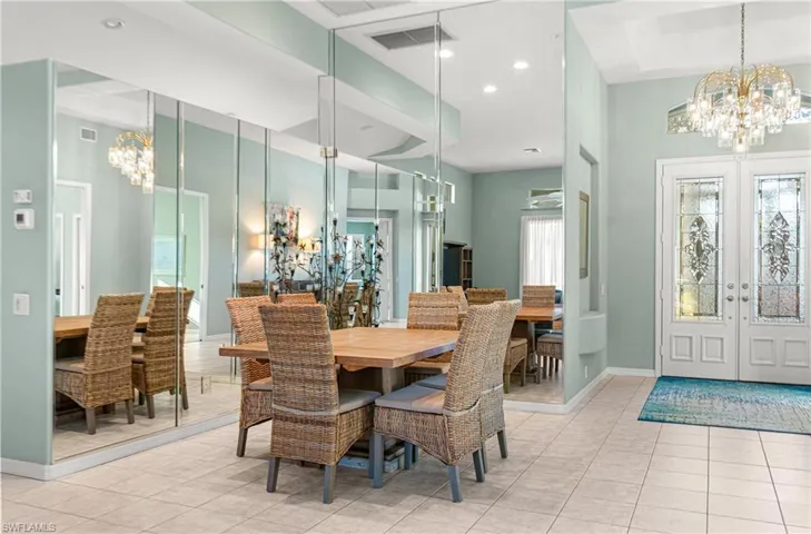 Dining and entry space with a chandelier, custom french doors, and light tile patterned floors
