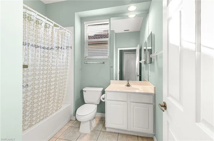 Bathroom with shower / bath combination with curtain, vanity, and light tile patterned floors