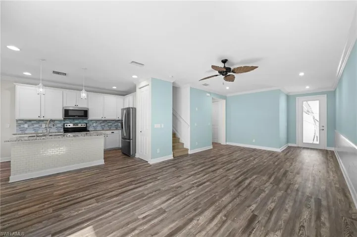 Kitchen with ceiling fan, hanging light fixtures, white cabinetry, appliances with stainless steel finishes, and dark hardwood / wood-style floors