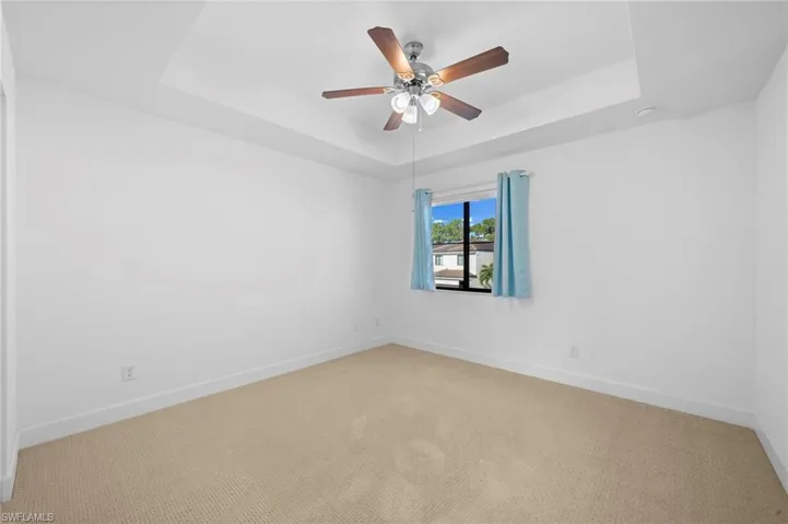 Unfurnished room with a raised ceiling, carpet flooring, and ceiling fan