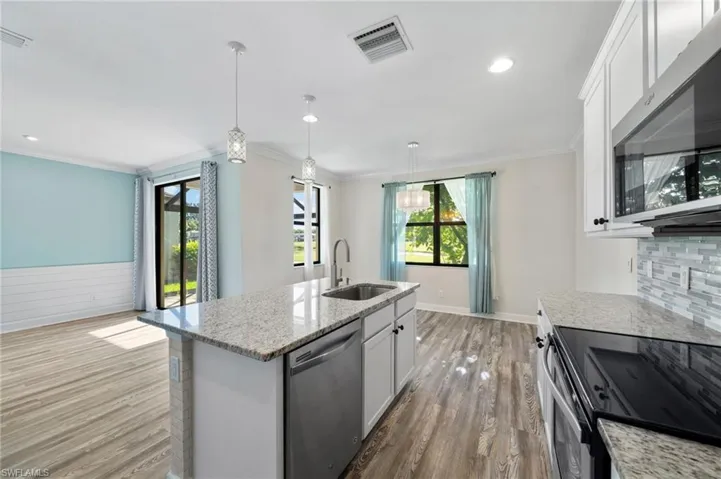 Kitchen with white cabinets, pendant lighting, sink, a kitchen island with sink, and stainless steel appliances