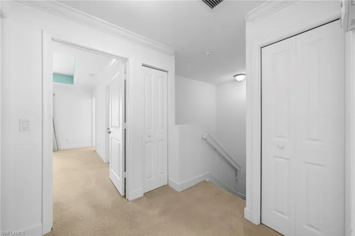Corridor featuring light carpet and crown molding
