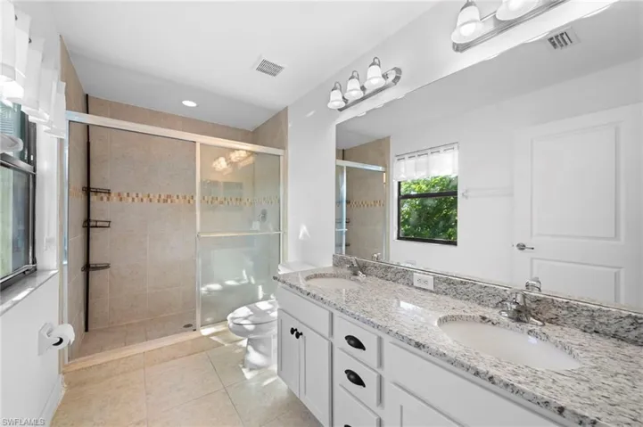 Bathroom with walk in shower, vanity, toilet, and tile patterned floors