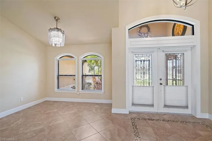 Tiled entryway with french doors and an inviting chandelier