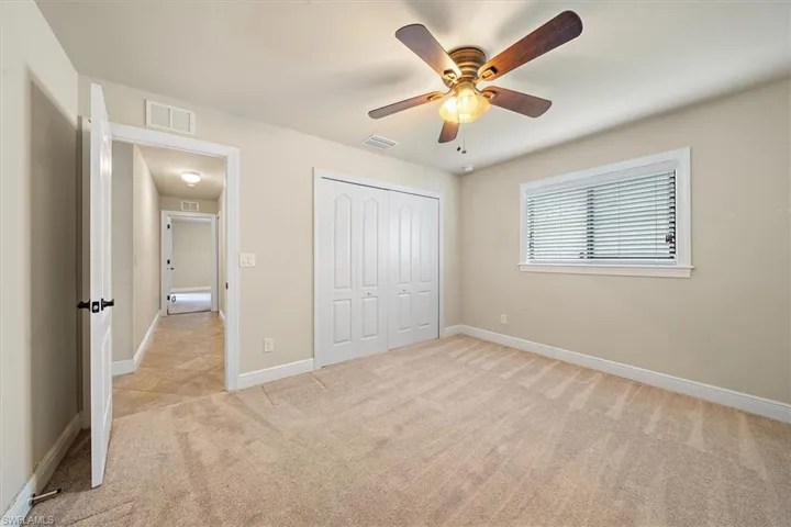 Unfurnished bedroom featuring ceiling fan, a closet, and light colored carpet