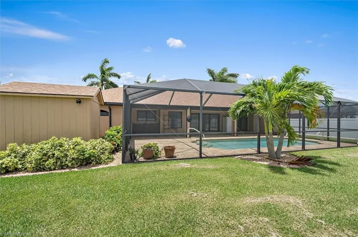 Back of property with a yard, screened enclosure, and a fenced in yard