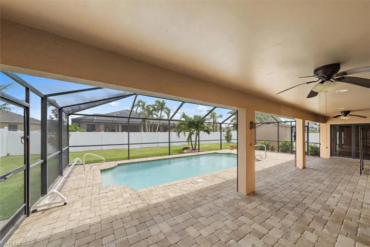 View of swimming pool with an outdoor structure, glass enclosure, a patio area, ceiling fan, and a yard