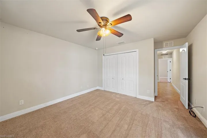 Unfurnished bedroom 3 featuring light carpet, a closet, and ceiling fan