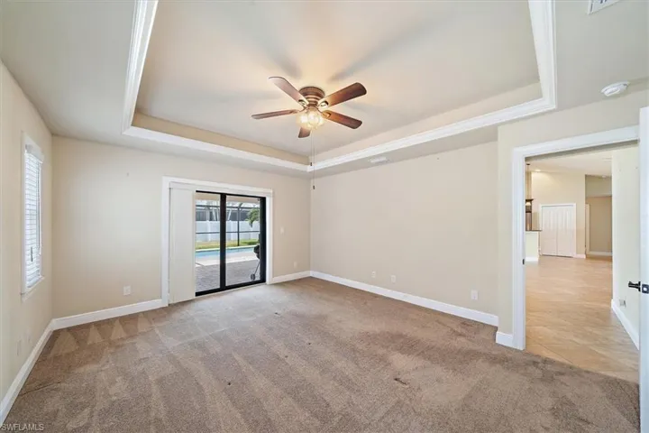 Spare room featuring light carpet, ceiling fan, and a raised ceiling