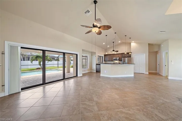 Unfurnished living room featuring high vaulted ceiling, ceiling fan, and light tile flooring
