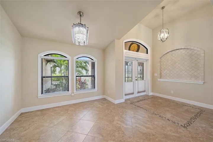Tiled entryway with an inviting chandelier and french doors