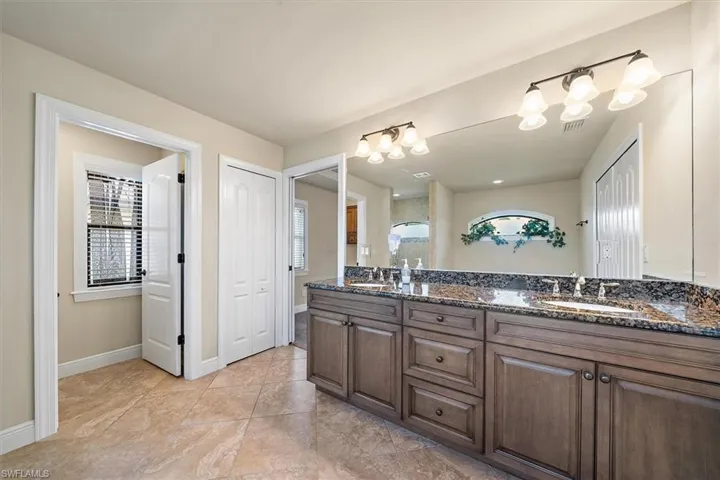 Bathroom with tile floors, plenty of natural light, oversized vanity, and dual sinks