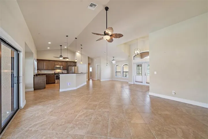 Unfurnished living room featuring high vaulted ceiling, french doors, ceiling fan, and light tile floors