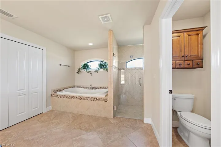 Master Bathroom featuring tile flooring, plus walk in shower, and toilet
