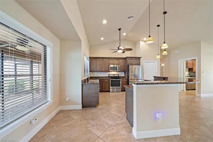 Kitchen featuring stainless steel appliances, sink, dark stone counters, and light tile flooring