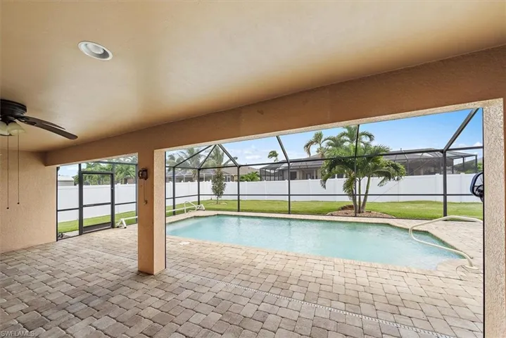 View of pool with a patio, enclosure, ceiling fan, and a yard