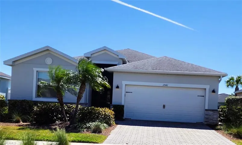 Ranch-style house with stucco siding, decorative driveway, an attached garage, and roof with shingles