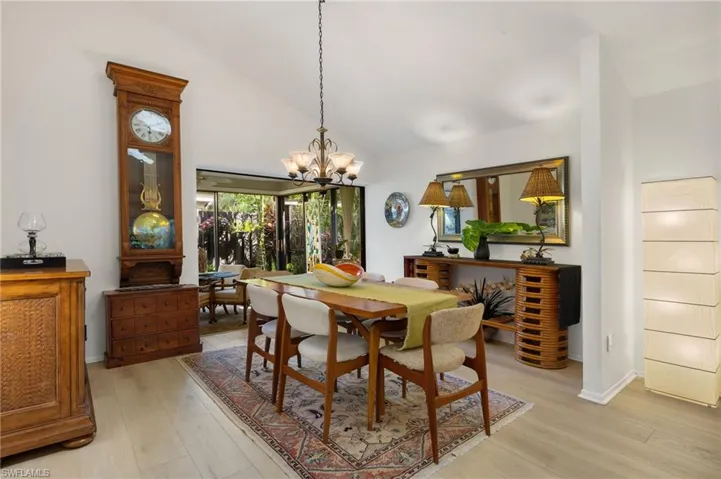 Dining space featuring baseboards, high vaulted ceiling, light wood finished floors, and a notable chandelier