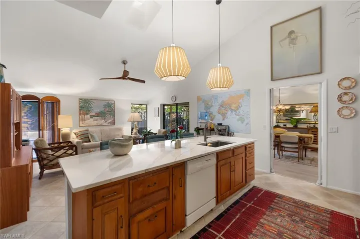 Kitchen with pendant lighting, open floor plan, white dishwasher, a sink, and an island with sink