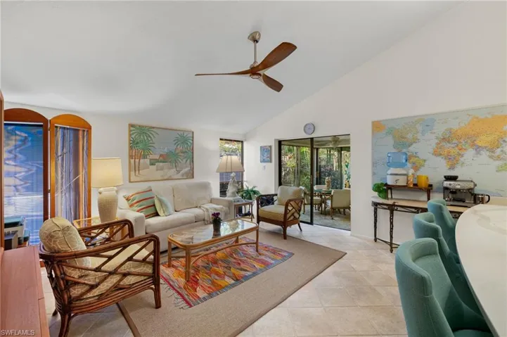 Living room with a ceiling fan, high vaulted ceiling, and light tile patterned floors