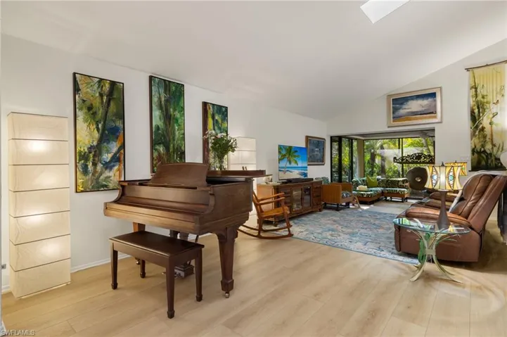 Sitting room featuring high vaulted ceiling, light wood finished floors, a skylight, and baseboards