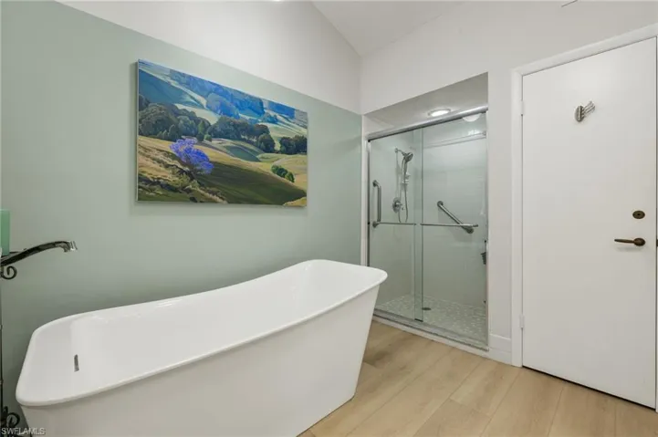 Bathroom featuring a freestanding tub, a shower stall, and wood finished floors