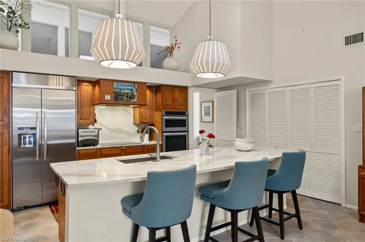 Kitchen with stainless steel appliances, brown cabinetry, hanging light fixtures, and a sink